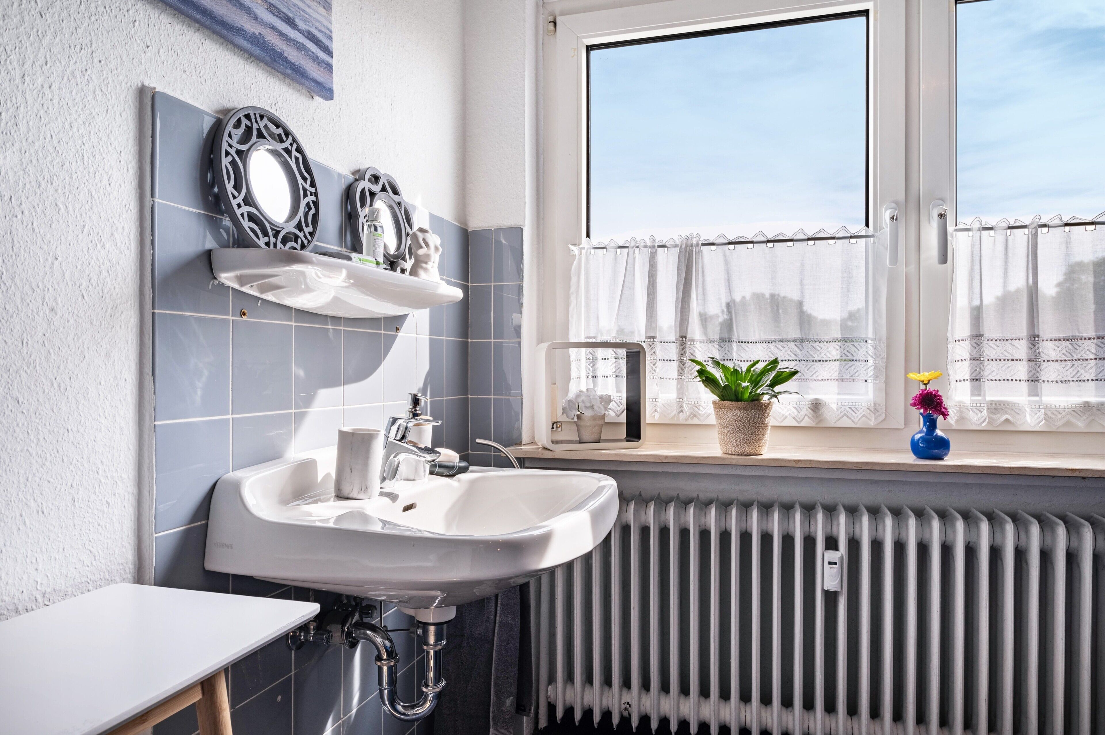 Ein Badezimmer mit Waschbecken, Spiegel und Fenster.