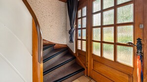 A wooden staircase with a textured wall and a large window with multiple panes.