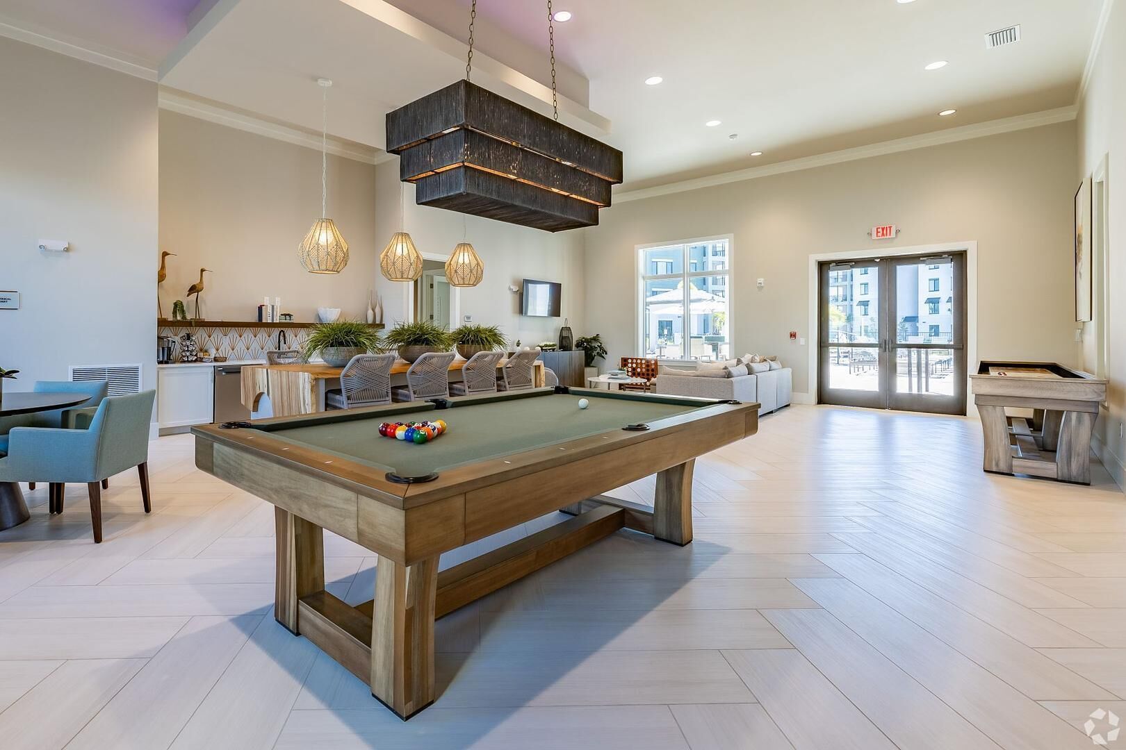 A spacious living area with a pool table, modern furniture, and a large window providing natural light.