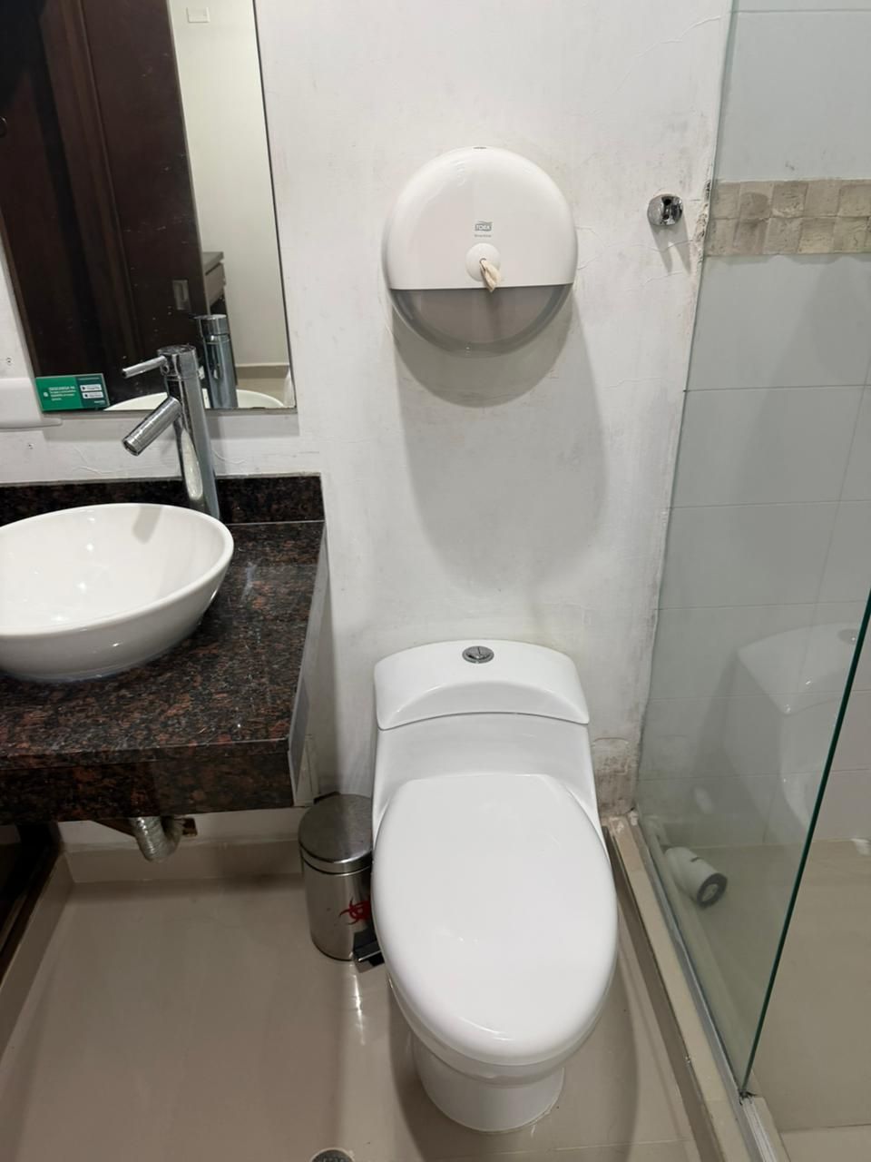 A bathroom with a white sink, a toilet, and a glass shower enclosure.