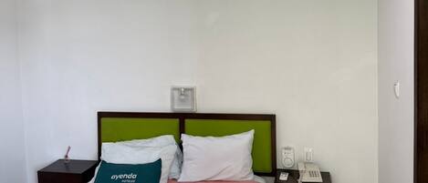 Ein Hotelzimmer mit Bett, Nachttisch, Telefon, Klimaanlage und Deckenventilator.
