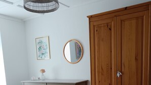 A bedroom with a bed, a wooden wardrobe, a bedside table with a vase, and a hanging light fixture. - In a house with garden, apartment with terrace near a lake. (Oderen)