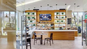 Un espace bar avec un comptoir en bois, des sièges et un écran de télévision.