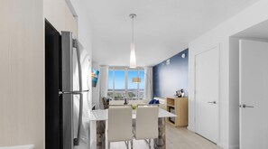 A modern kitchen with a dining area, large windows, and a view of the cityscape. - High-Floor 1BR · Intracoastal View · Resort & Pool (Hallandale Beach)