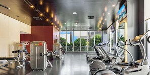 Ein Fitnessraum mit Cardiogeräten, Gewichten und großen Fenstern mit Blick ins Freie.