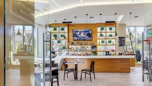 A bar area with a wooden counter, seating, and a TV screen. - High-Floor Studio | Intracoastal, Sleeps 4 (Hallandale Beach)