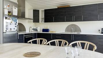 A modern kitchen with dark cabinets, a white countertop, and a dining table with chairs.