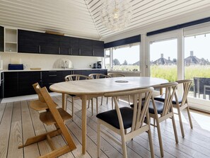 A modern kitchen with dark cabinets, a white countertop, and a large window overlooking a green landscape.