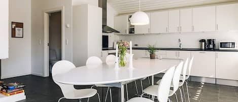 A modern kitchen with white cabinets, a round dining table, and white chairs.