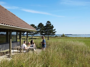 A covered outdoor seating area with a view of a lake and trees. - 4 Person Holiday Park Home in Karrebaeksminde (Karrebæksminde)