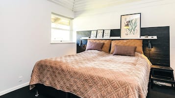 A bedroom with a bed, a window, a headboard, and wall art.