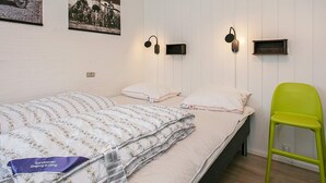 Camera da letto con due letti, una poltrona verde e lampade a parete.