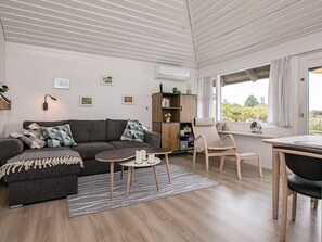 A modern living room with a sofa, a small table, a chair, and a bookshelf.