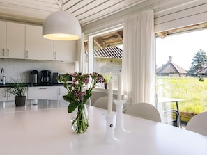 A modern kitchen with white cabinets, a large window, and a table with a vase of flowers. - 4 Person Holiday Park Home in Karrebaeksminde (Karrebæksminde)