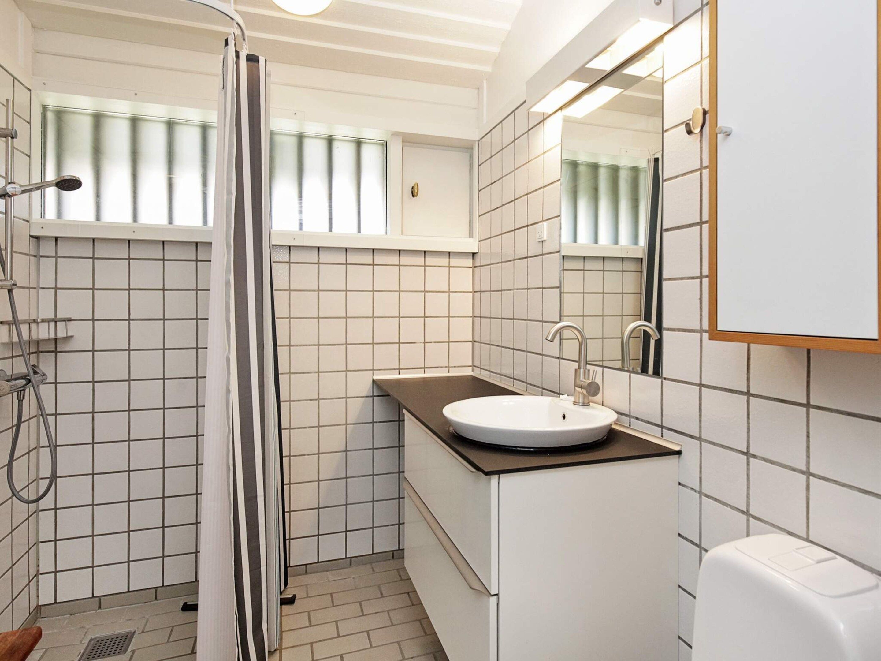 A bathroom with a shower, a sink, and a mirror.