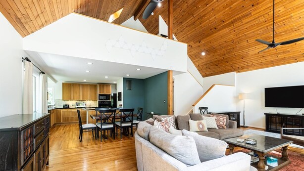 A spacious living area with a wooden ceiling, a sofa, a coffee table, and a TV.