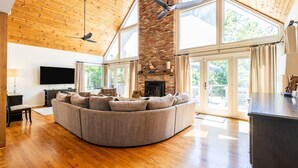 A spacious living area with a large curved sofa, a fireplace, and a television.