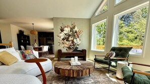 A spacious living room with a round coffee table, a sofa, a chair, and a dining area in the background.