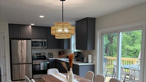 A modern kitchen with dark cabinets, stainless steel appliances, and a dining area with a long table and chairs.