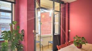 A room with a sliding glass door leading to a balcony, a dining table with chairs, and a potted plant. - Spacious Stay for 9 in Antwerp (Antwerp)