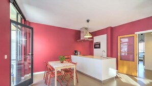 A modern kitchen with a central island, a dining area with wooden chairs, and a large sliding glass door. - Spacious Stay for 9 in Antwerp (Antwerp)