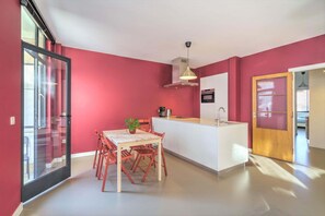 A modern kitchen with a central island, a dining area with wooden chairs, and a large sliding glass door. - Spacious Stay for 9 in Antwerp (Antwerp)