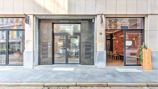 A building with a glass door entrance, a sign reading 'BELGA & CO. SIMPLE PLEASURES,' and a 'HELLO' sign outside. - Spacious Stay for 9 in Antwerp (Antwerp)