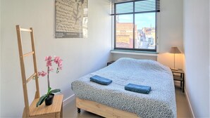 A bedroom with a bed, a window, a lamp, and a plant. - Spacious Stay for 9 in Antwerp (Antwerp)