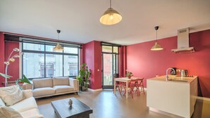 A modern living room with a sofa, coffee table, and dining area with chairs. - Spacious Stay for 9 in Antwerp (Antwerp)
