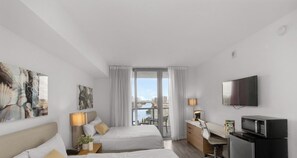 Ein Hotelzimmer mit Bett, Schreibtisch, Fernseher und Blick auf die Stadtlandschaft.