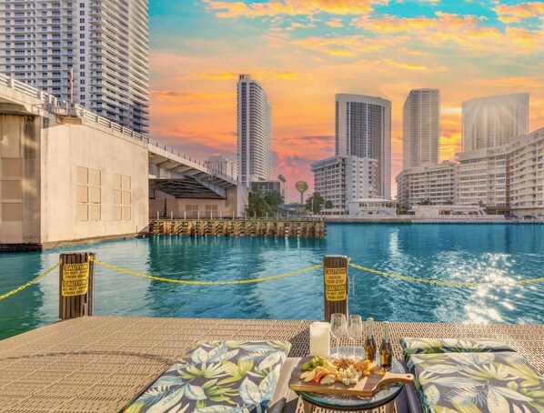 A waterfront hotel with high-rise buildings in the background, a swimming pool, and caution signs along the poolside. - High-Floor Waterway · 2BR Resort Suite & Balcony (Hallandale Beach)