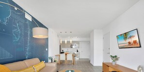 Ein modernes Wohnzimmer mit Sofa, Couchtisch und Essbereich, im Hintergrund eine Küche.