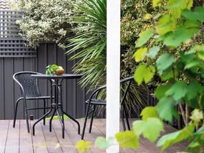 A patio with a round table and two chairs, surrounded by greenery and a fence. - Stunning two story home in town centre (Margaret River)