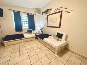 Une chambre avec deux lits, une fenêtre avec des rideaux, une carte accrochée au mur et une petite table avec une lampe.