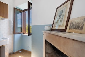 A bathroom with a toilet, sink, and open window. There is a framed picture on the wall.