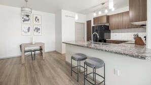 Una cucina moderna con un piano di lavoro in marmo, elettrodomestici in acciaio inossidabile e un angolo bar con sgabelli.