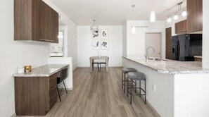 Eine moderne Küche mit Holzausstattung, einer Marmorarbeitsplatte, einer Essecke mit Tisch und Stühlen sowie einem Kühlschrank.