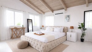 A bedroom with a large bed, bedside tables, a desk, a potted plant, and a ceiling fan. - Cozy 2bdrm private home/Cayman Brac W/ AC, gym, WiFi & outdoor tub (Cayman Islands)