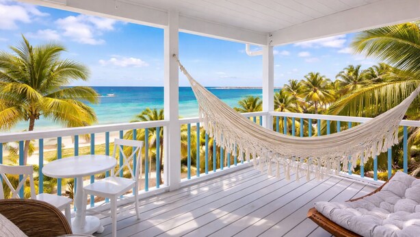A hammock on a wooden deck with a view of the ocean and palm trees. - Cozy 2bdrm private home/Cayman Brac W/ AC, gym, WiFi & outdoor tub (Cayman Islands)
