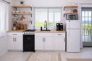 A kitchen with white cabinets, a stove, a sink, and a microwave.