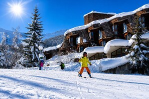 Un centro de esquí con edificios de madera, árboles cubiertos de nieve y esquiadores.