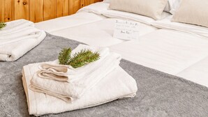A hotel room with wooden panel walls, a bed with white linens, and a note on the bed. - Petit Chalet Pila (Pila)