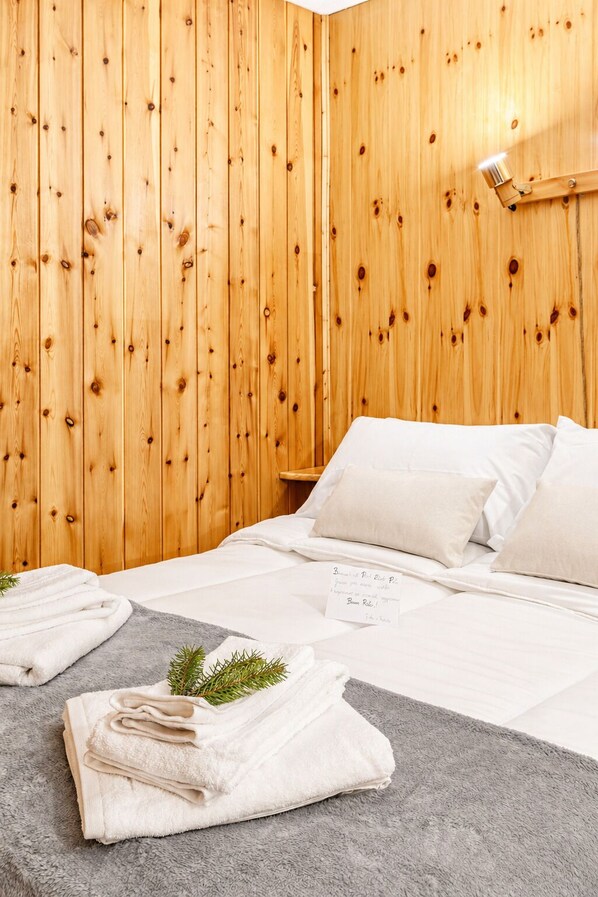 Habitación de hotel con paredes de madera, una cama con ropa blanca y una nota sobre la cama.