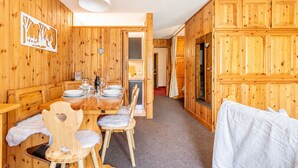 A wooden interior with a dining area, a bed, and a hallway leading to a bathroom. - Petit Chalet Pila (Pila)