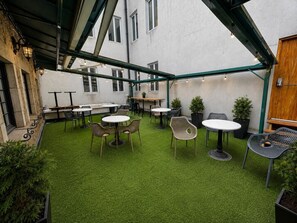 An outdoor patio area with artificial grass, tables, chairs, and potted plants. - Boutique Old Montreal Suite-1B (Montreal)