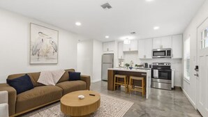 A modern kitchen with white cabinets, stainless steel appliances, and a central island with stools.