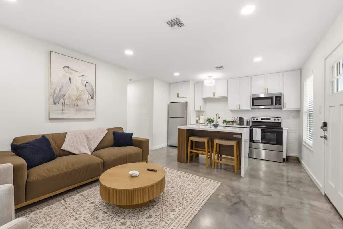 A modern kitchen with white cabinets, stainless steel appliances, and a central island with stools.
