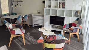 Ein Wohnzimmer mit einer weißen Unterhaltungseinheit, einem Esstisch mit Stühlen und einem Fernseher.