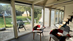 Ein sonnendurchflutetes Zimmer mit großen Fenstern, einem Tisch und zwei Stühlen.