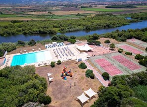 Vista aérea de un resort con piscina, canchas de tenis y un parque infantil.